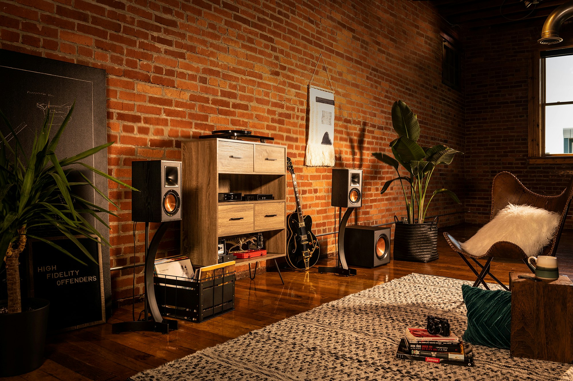 Klipsch Reference bookshelf speakers and subwoofer next to a guitar and wood cabinet