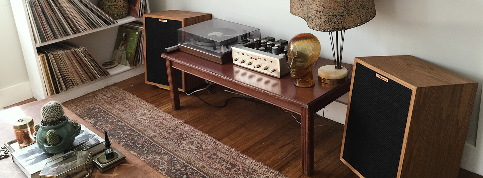 Two Heresy speakers flanking a wood table with a turntable and amplifier