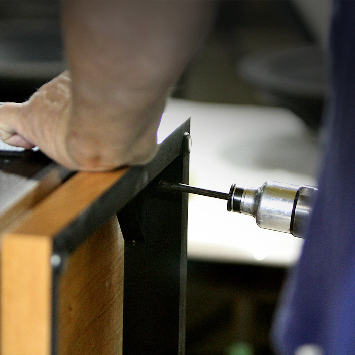 A close up view of a craftsman at the Hope Arkansas Klipsch Factory hand assembling a Heritage Speaker with a screwgun mobile