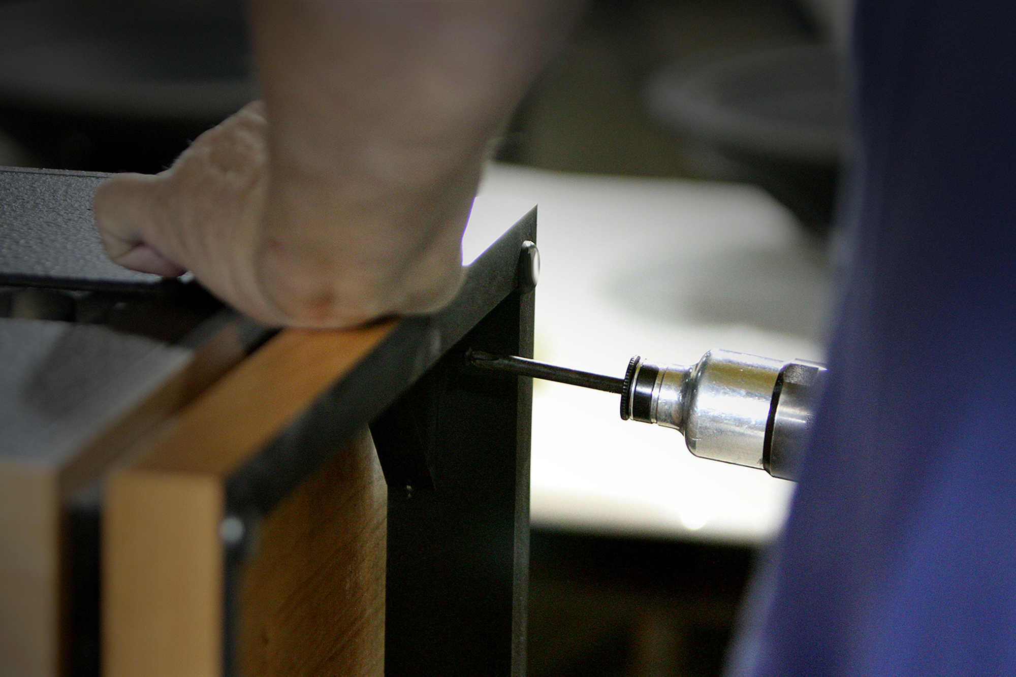 A close up view of a craftsman at the Hope Arkansas Klipsch Factory hand assembling a Heritage Speaker with a screwgun 2000x1333
