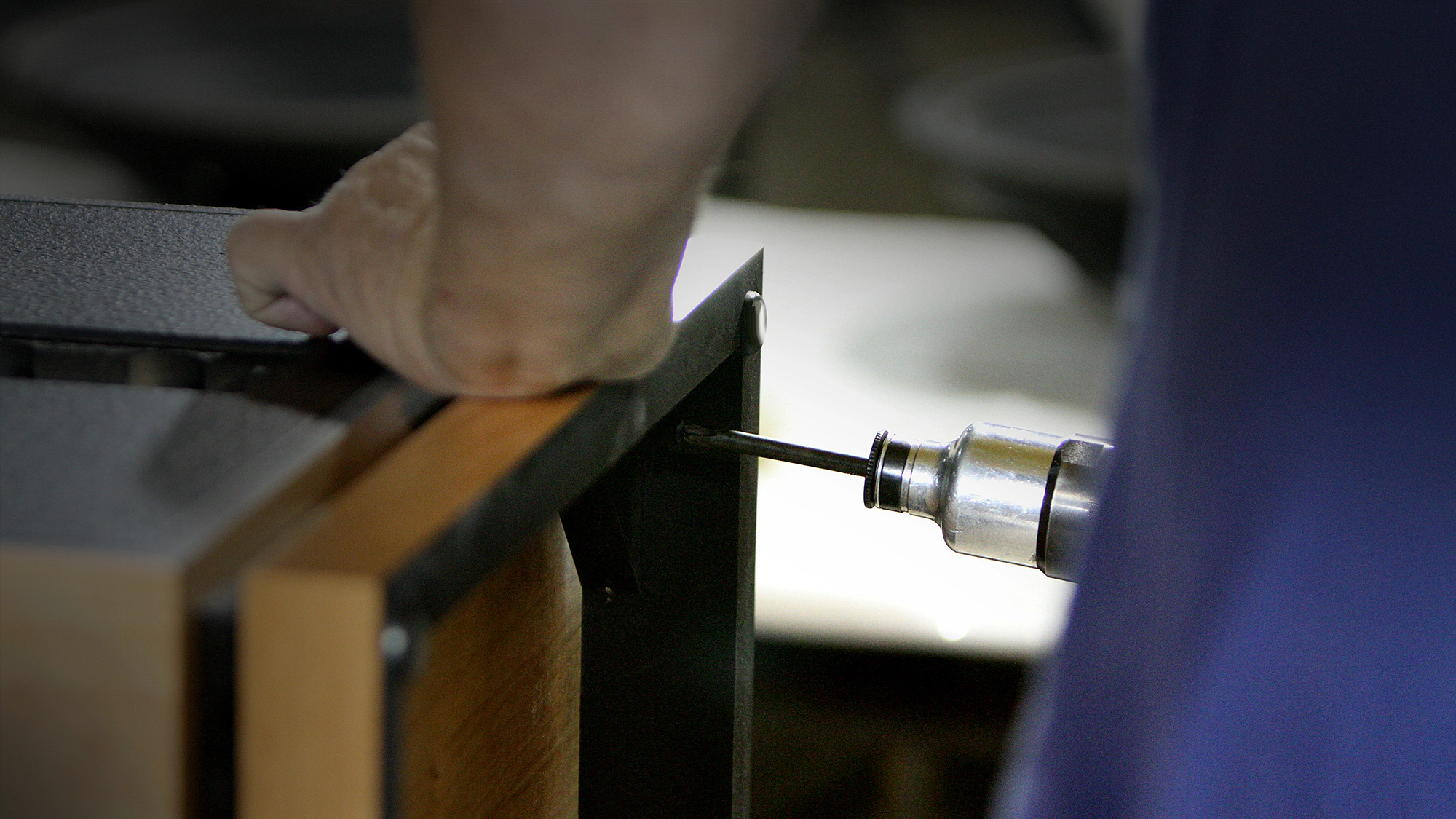 A close up view of a craftsman at the Hope Arkansas Klipsch Factory hand assembling a Heritage Speaker with a screwgun