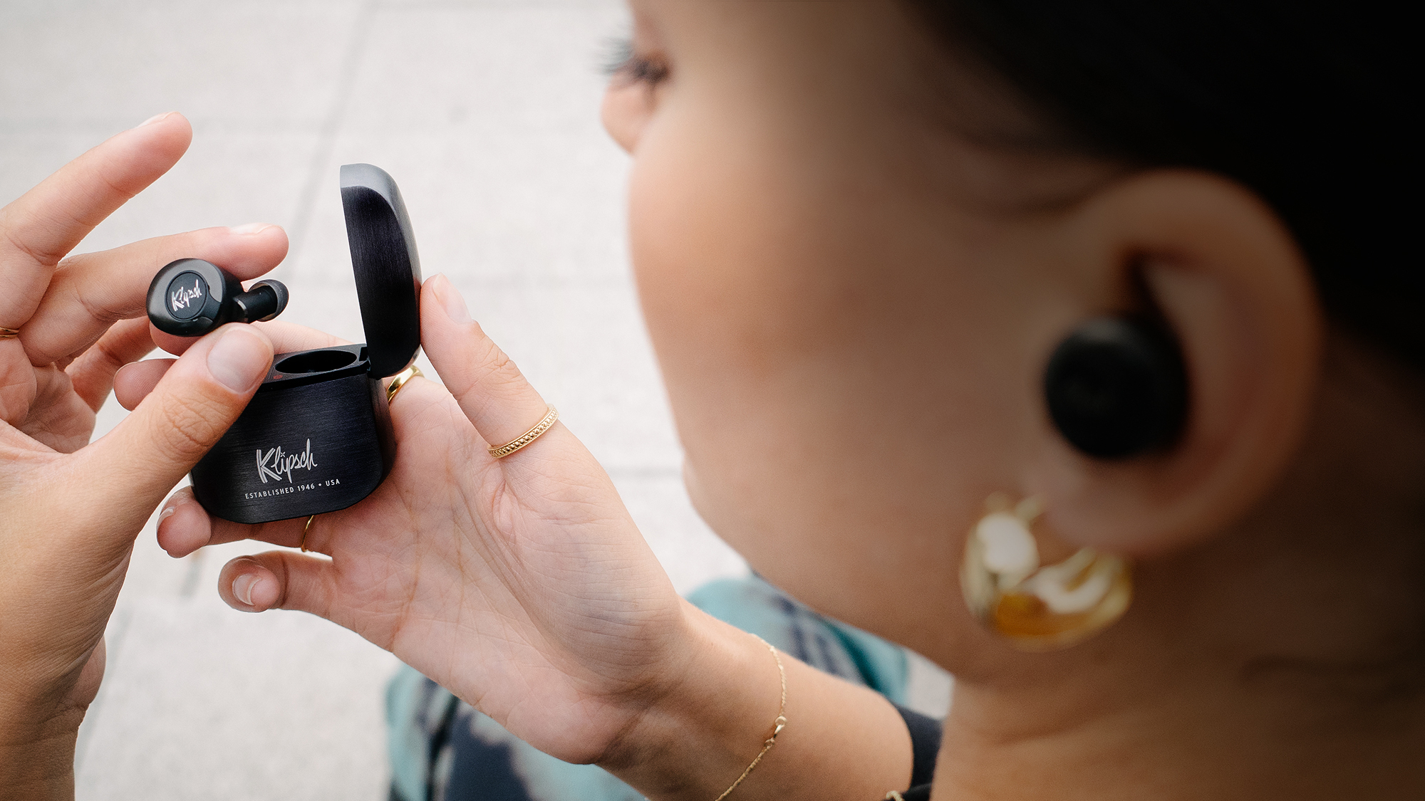 Closeup of a woman looking at her Gunmetal Klipsch T5 II True Wireless ANC Earphones Desktop