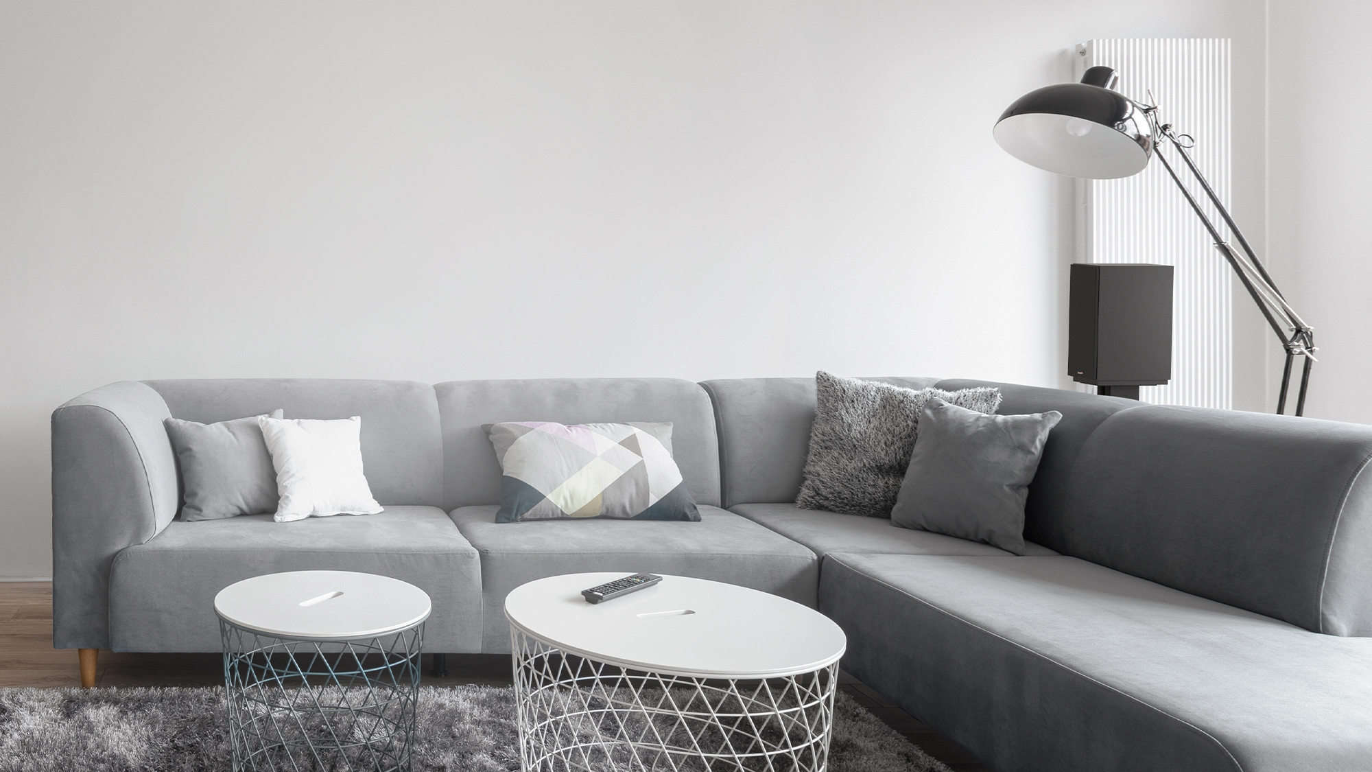 KD 51 M Speaker on a stand behind a grey sectional sofa