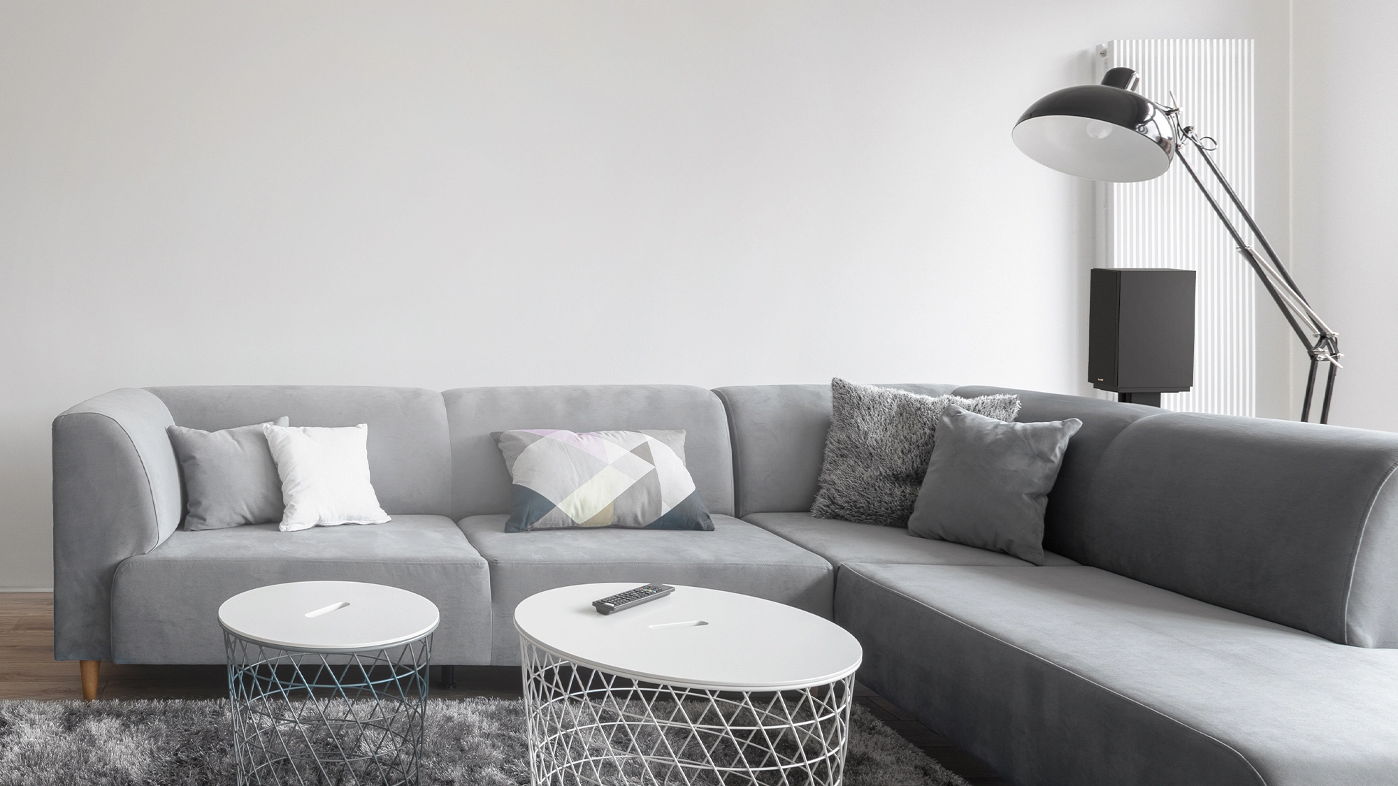 KD 51 M Speaker on a stand behind a grey sectional sofa