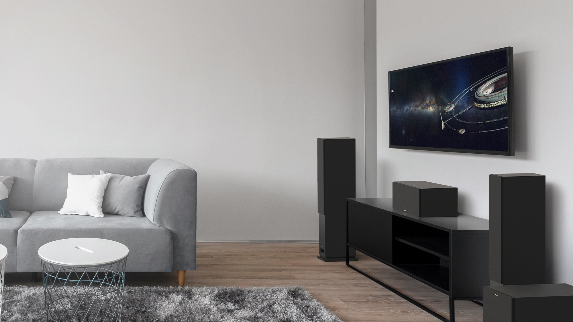 KD Series tower system with grilles on and a black credenza in a living room with grey couch