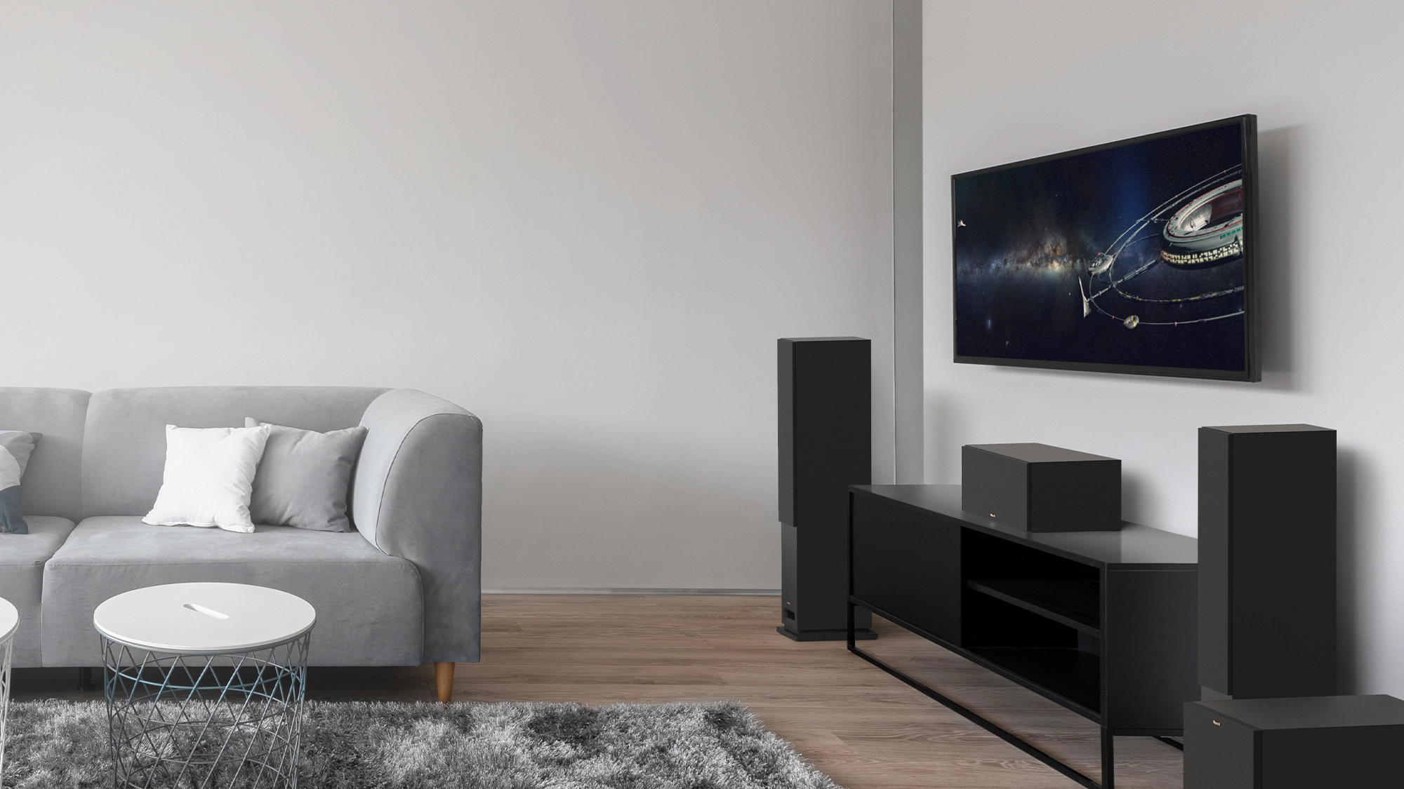 KD Series tower system with grilles on and a black credenza in a living room with grey couch