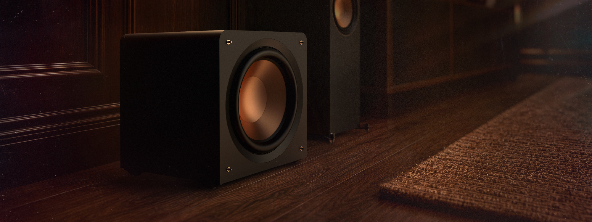 Klipsch Compact Subwoofer on floor beside media console and floor speakers 2000x750px