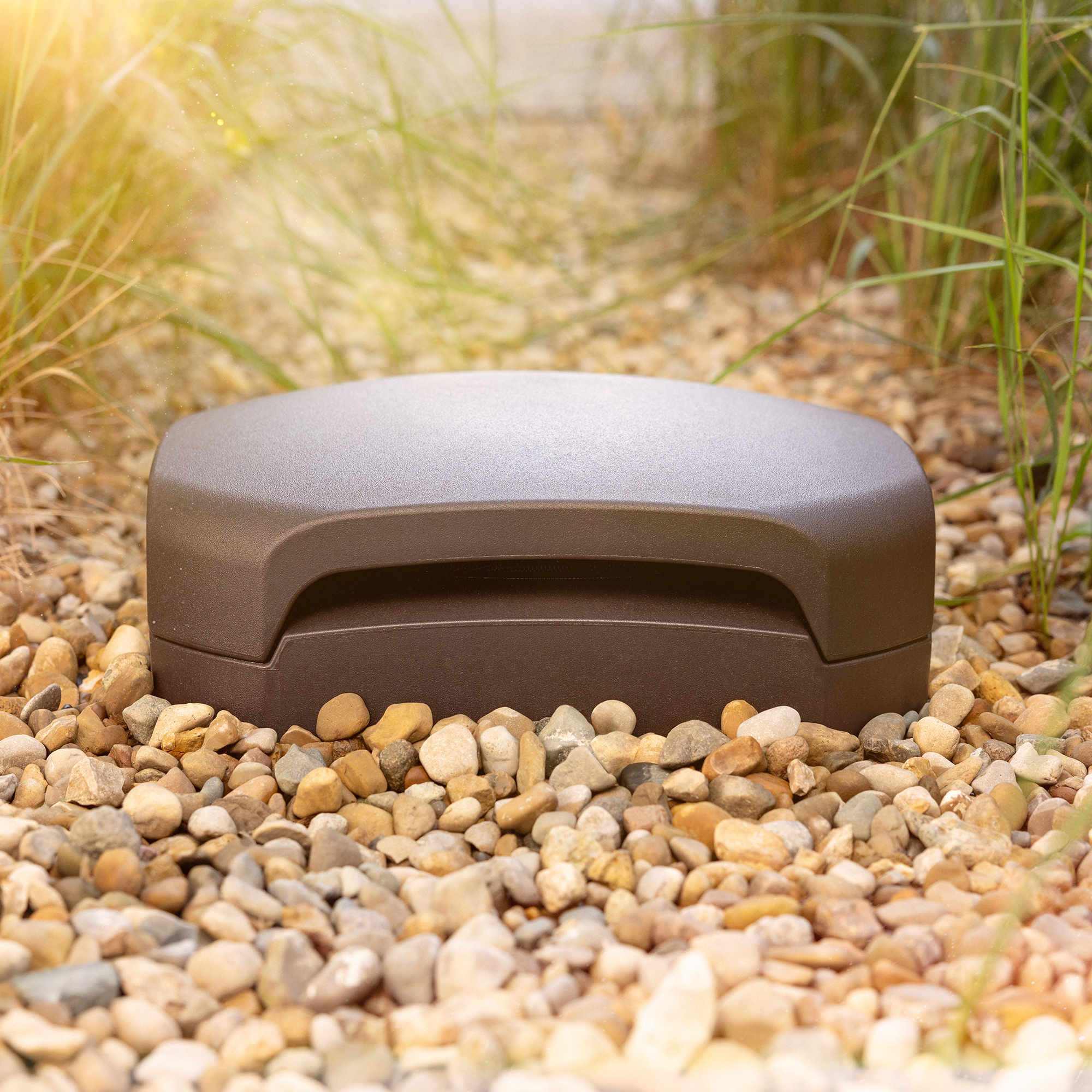 Klipsch Courtyard Subwoofer outside buried in patio gravel at golden hour 2000x2000