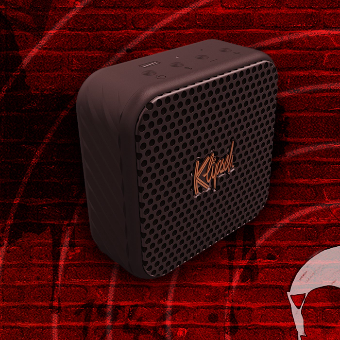 Klipsch Daredevil Partnership Klipsch Austin portable speaker against dark red brick wall with circles emanating 2000x2000