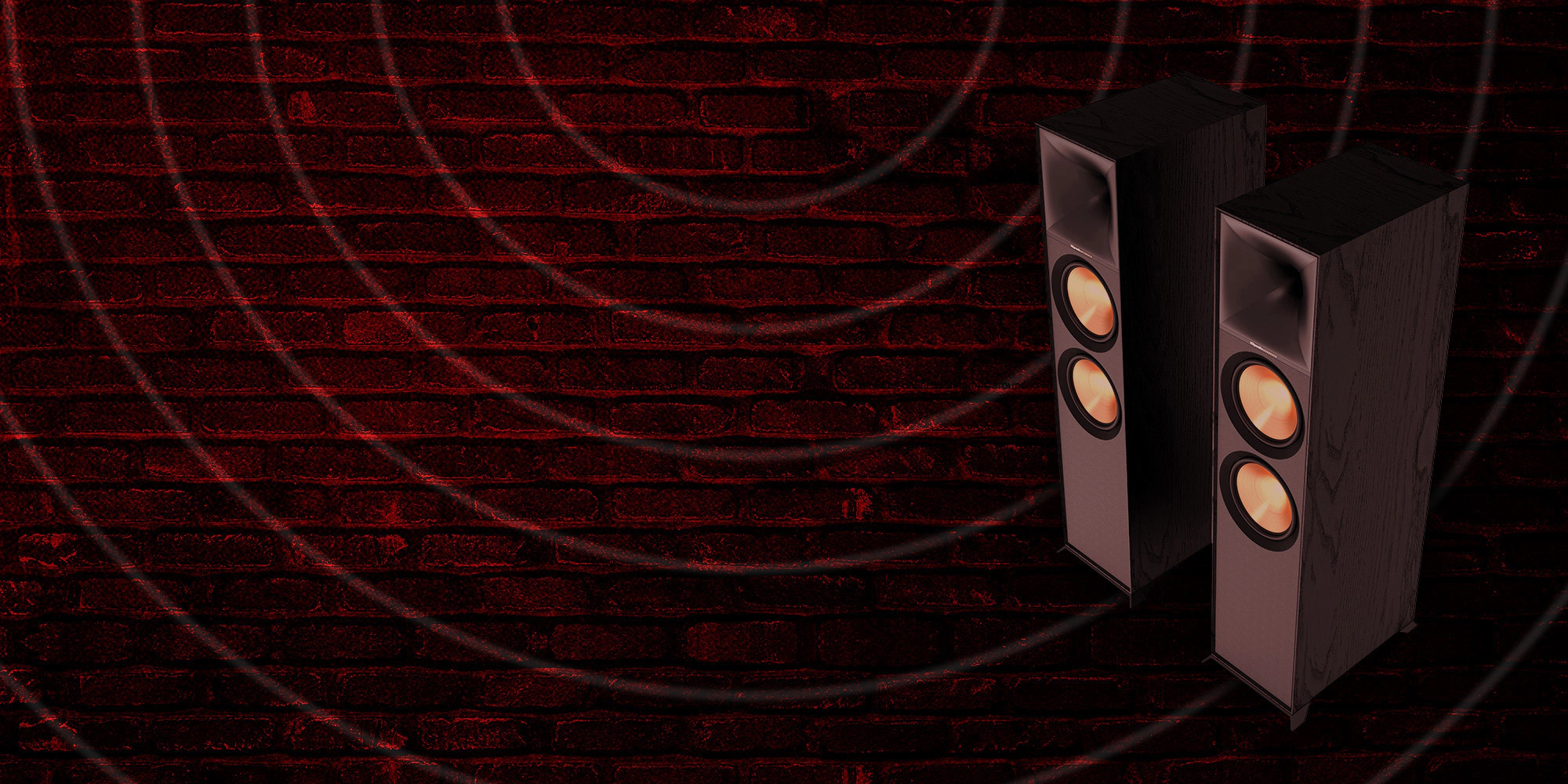 Klipsch Daredevil Partnership Klipsch Reference Premiere floorstanding speakers against dark red brick wall with circles emanating 2000x1000