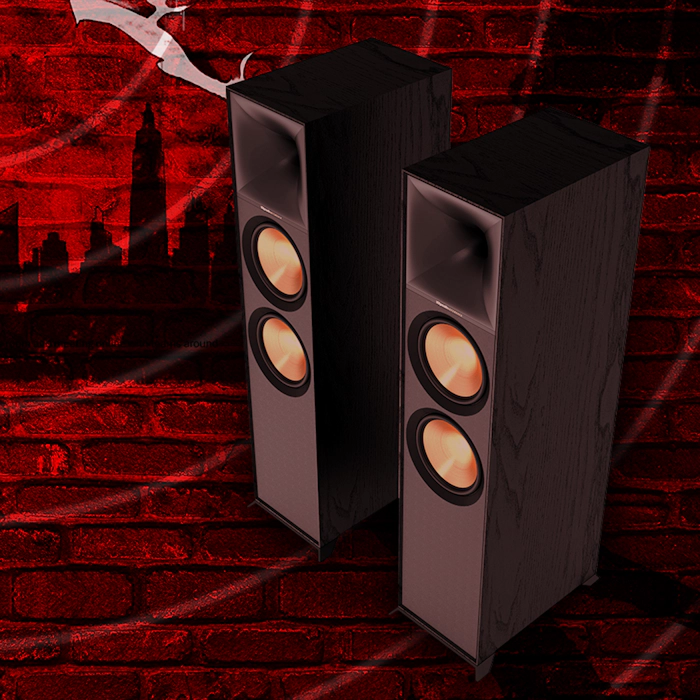 Klipsch Daredevil Partnership Klipsch Reference Premiere floorstanding speakers against dark red brick wall with circles emanating 2000x2000