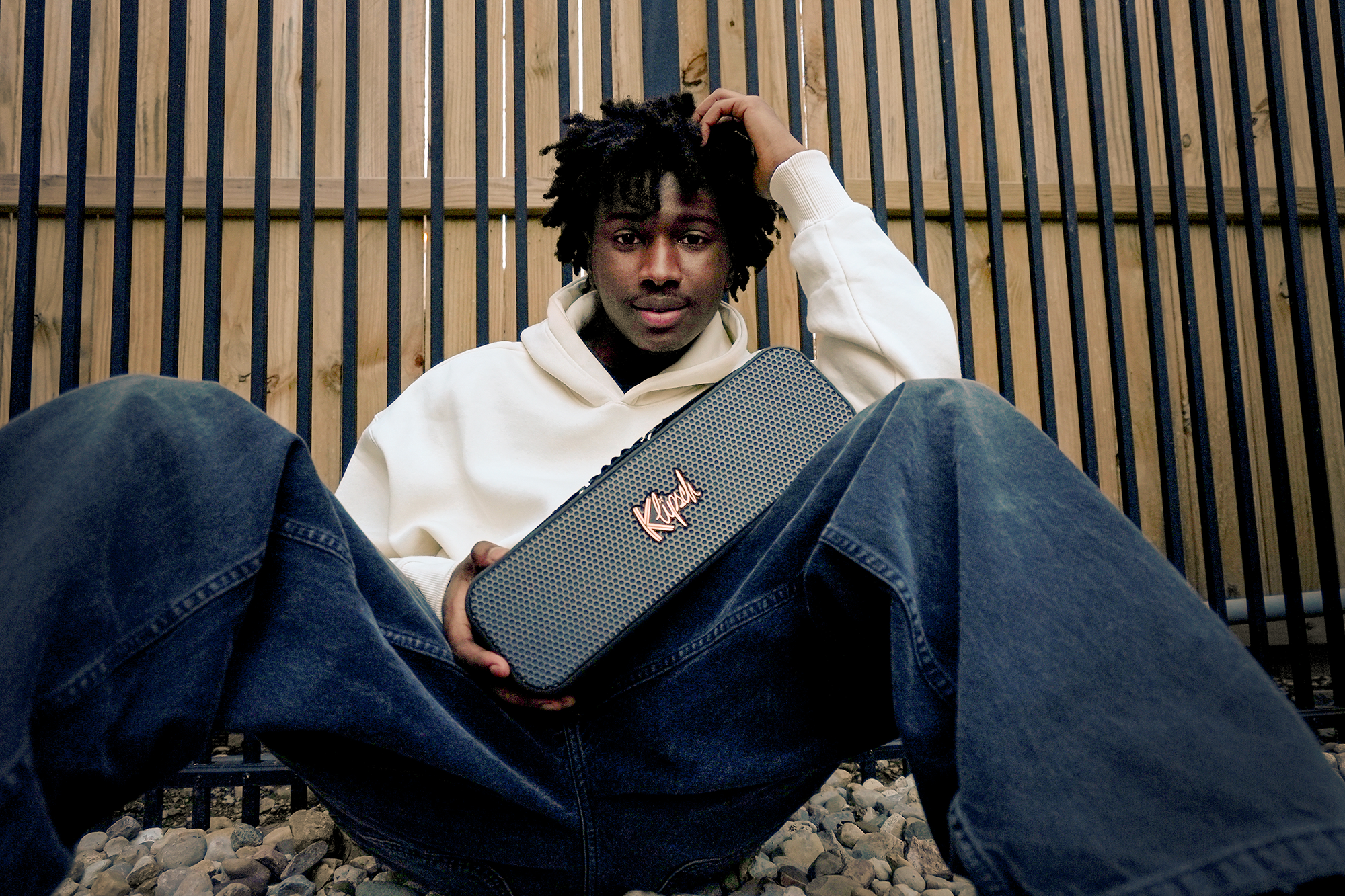 Klipsch Detroit held by cool guy sitting outside against fence 2000x1333