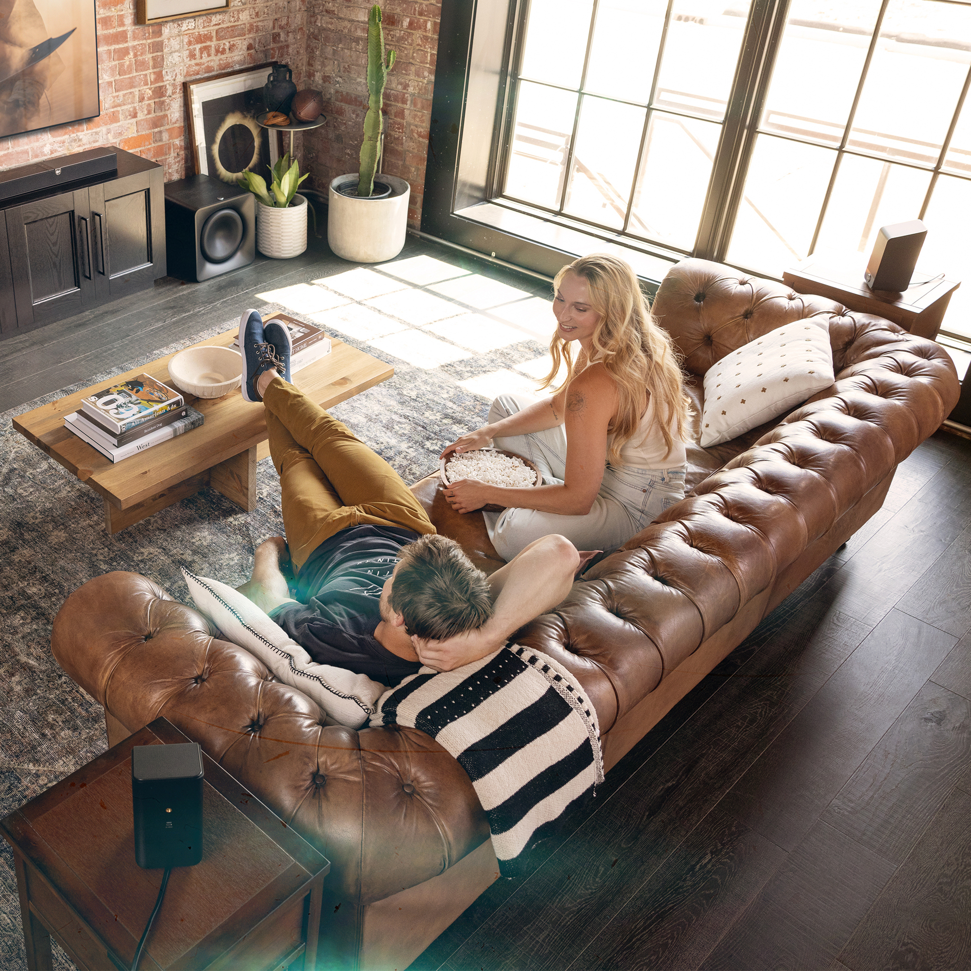 Klipsch Flexus CORE 300 BK and SURR 200 and two SUB 200 in living room with couple watching tv on leather couch 2000x2000