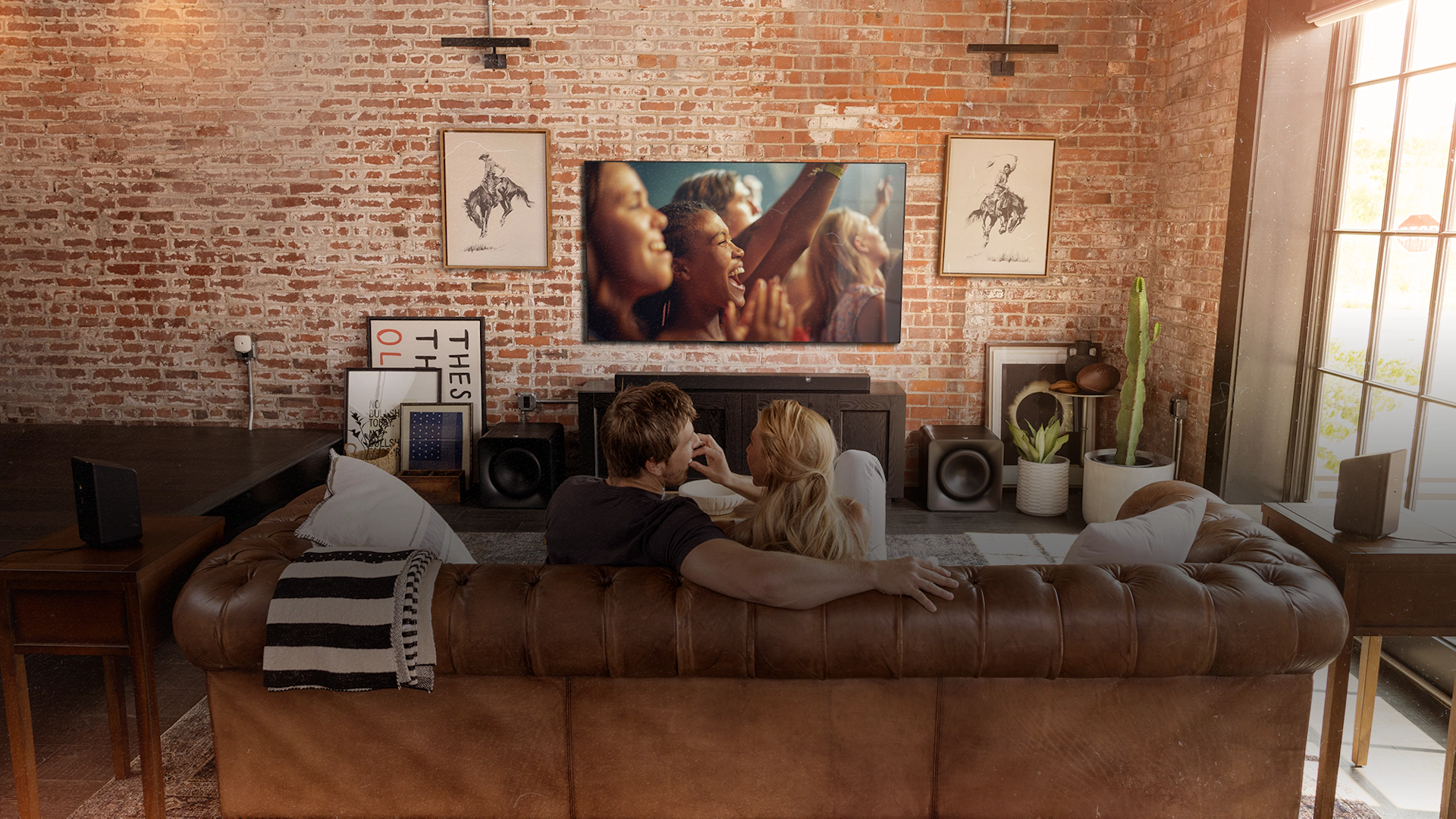 Klipsch Flexus CORE 300 BK and SURR 200 and two SUB 200 in living room with couple watching tv on leather couch 2000x1333