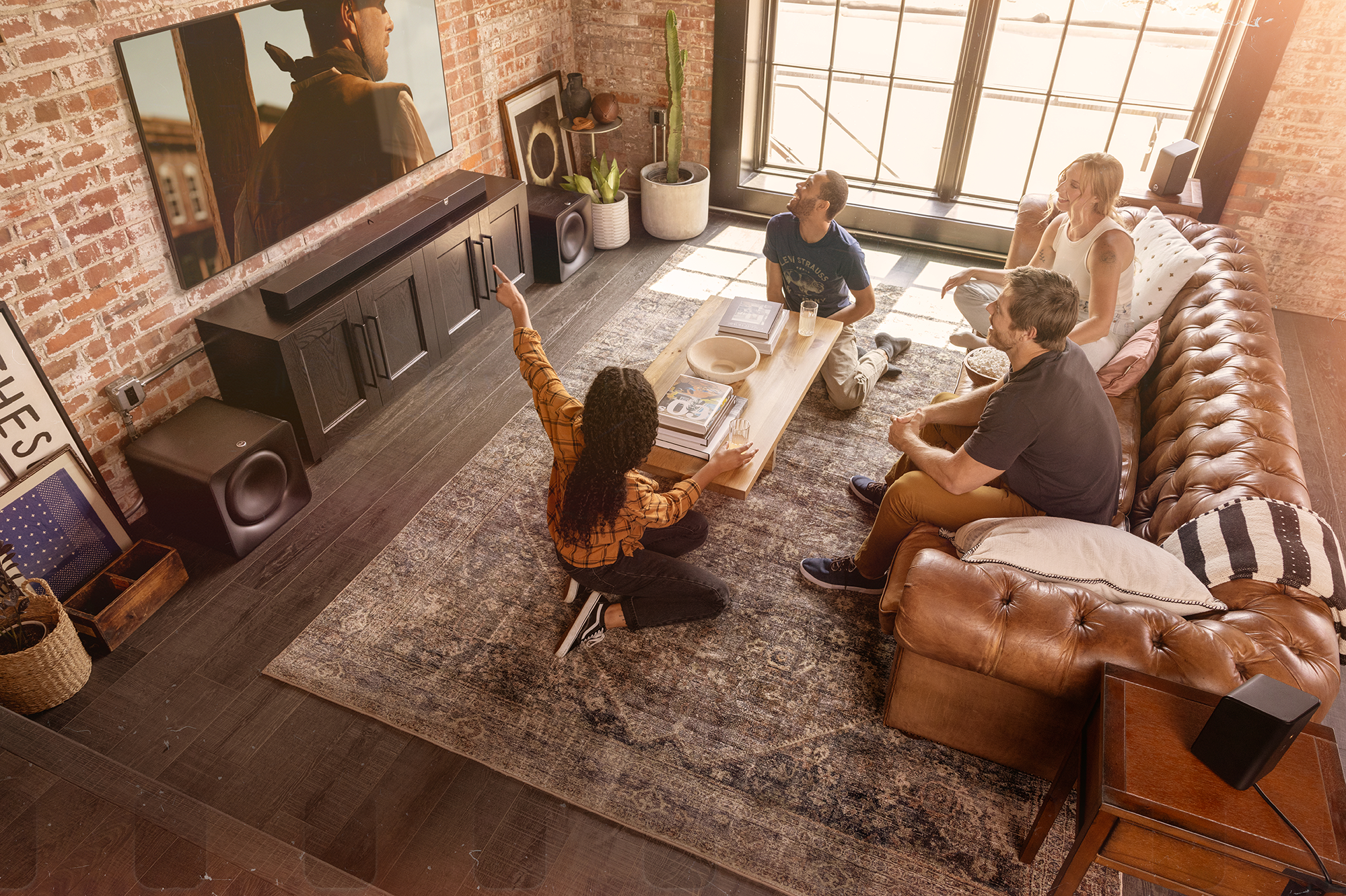 Klipsch Flexus CORE 300 BK and two SUB 200 in living room with group of friends interacting in front of tv 2000x1333