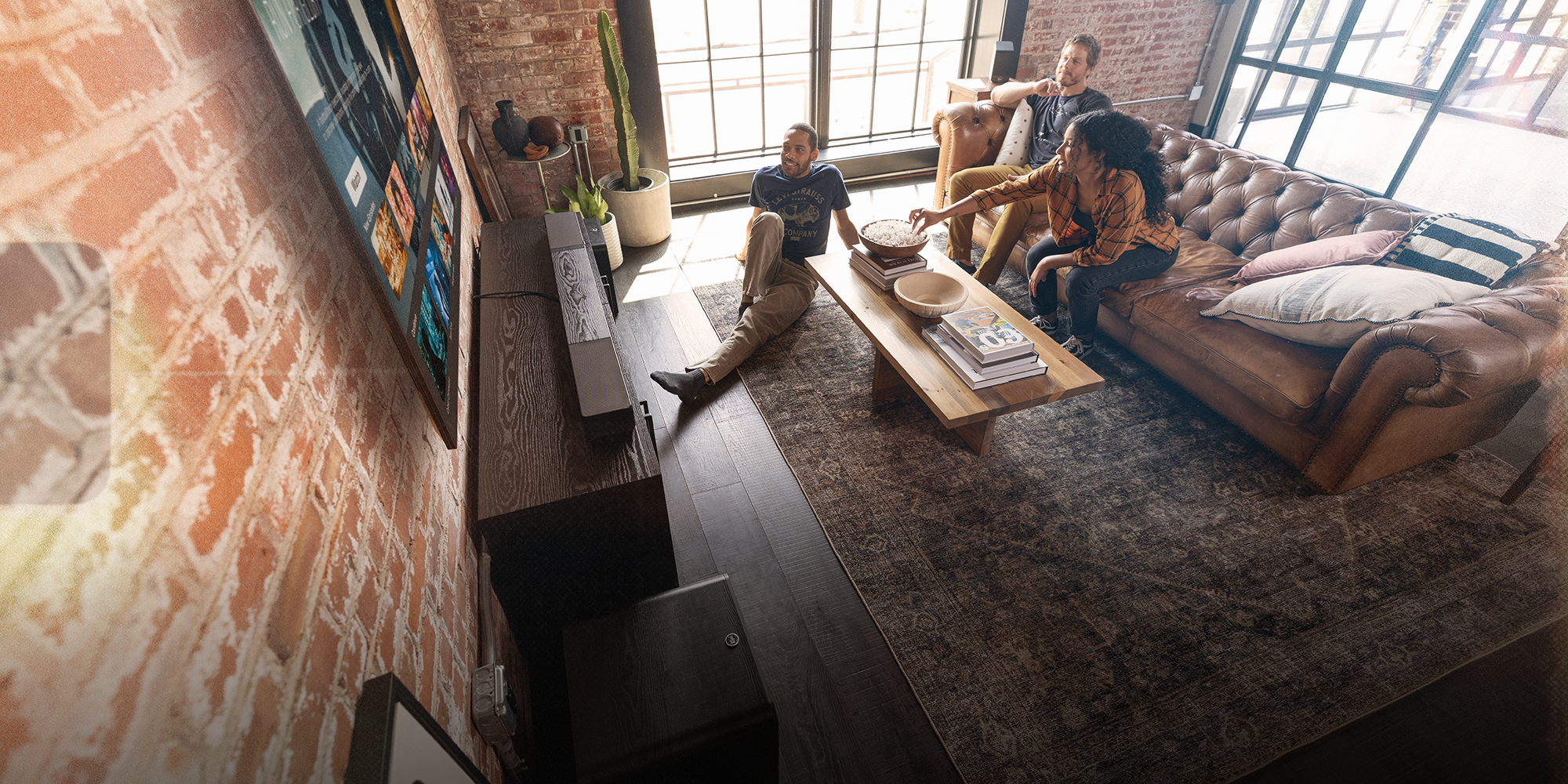 Klipsch Flexus Core 300 Sub 200 Surr 200 in brick loft with friends engaged watching tv with overlay 2000x1000