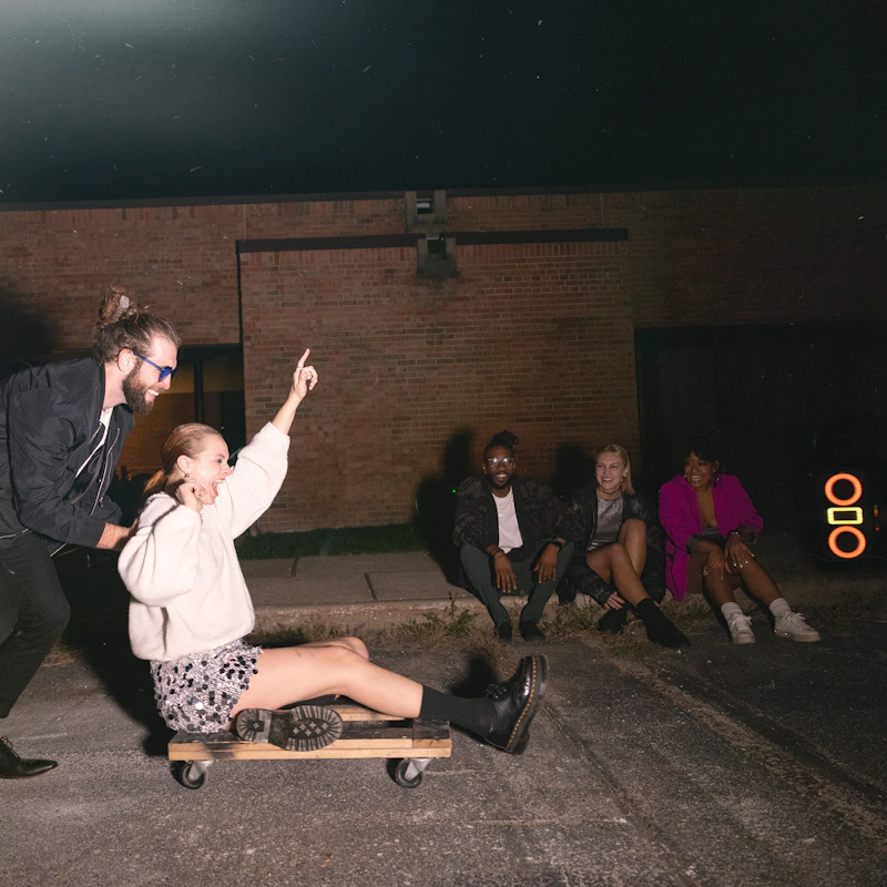 Klipsch Party Speakers Vibe guy pushing woman on furniture dolley in parking lot 2000x2000