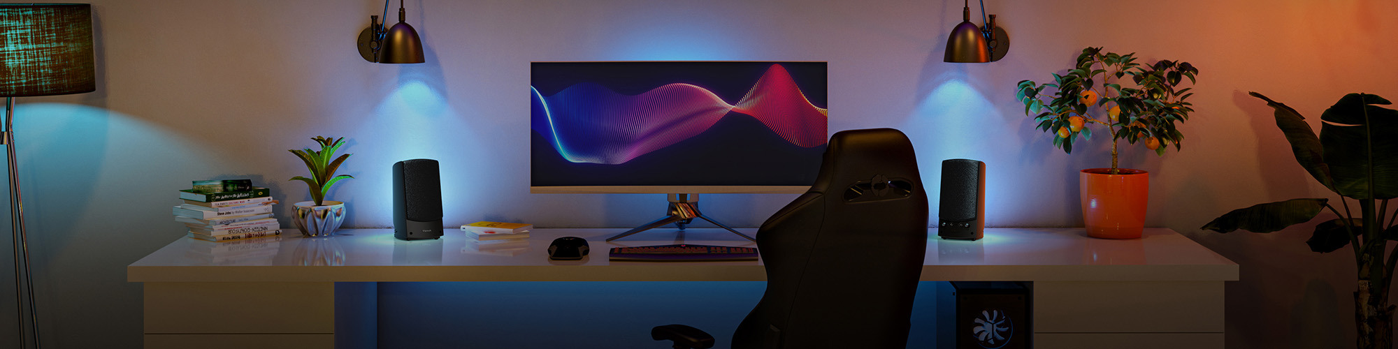 Klipsch Pro Media 2 on long desktop with low lighting and waves on screen 2000x500