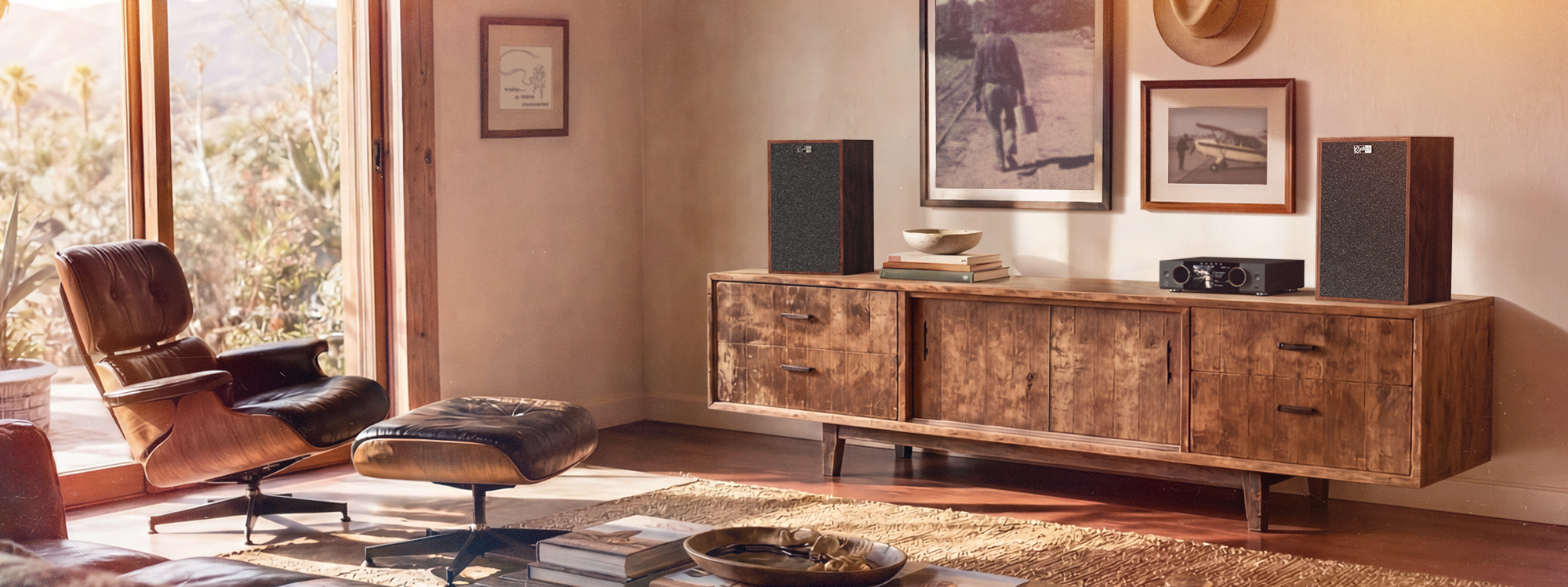 Klipsch Rebellion Premium Heritage Bookshelf Loudspeakers on long sun soaked living room console beside Eames chair 2000x750