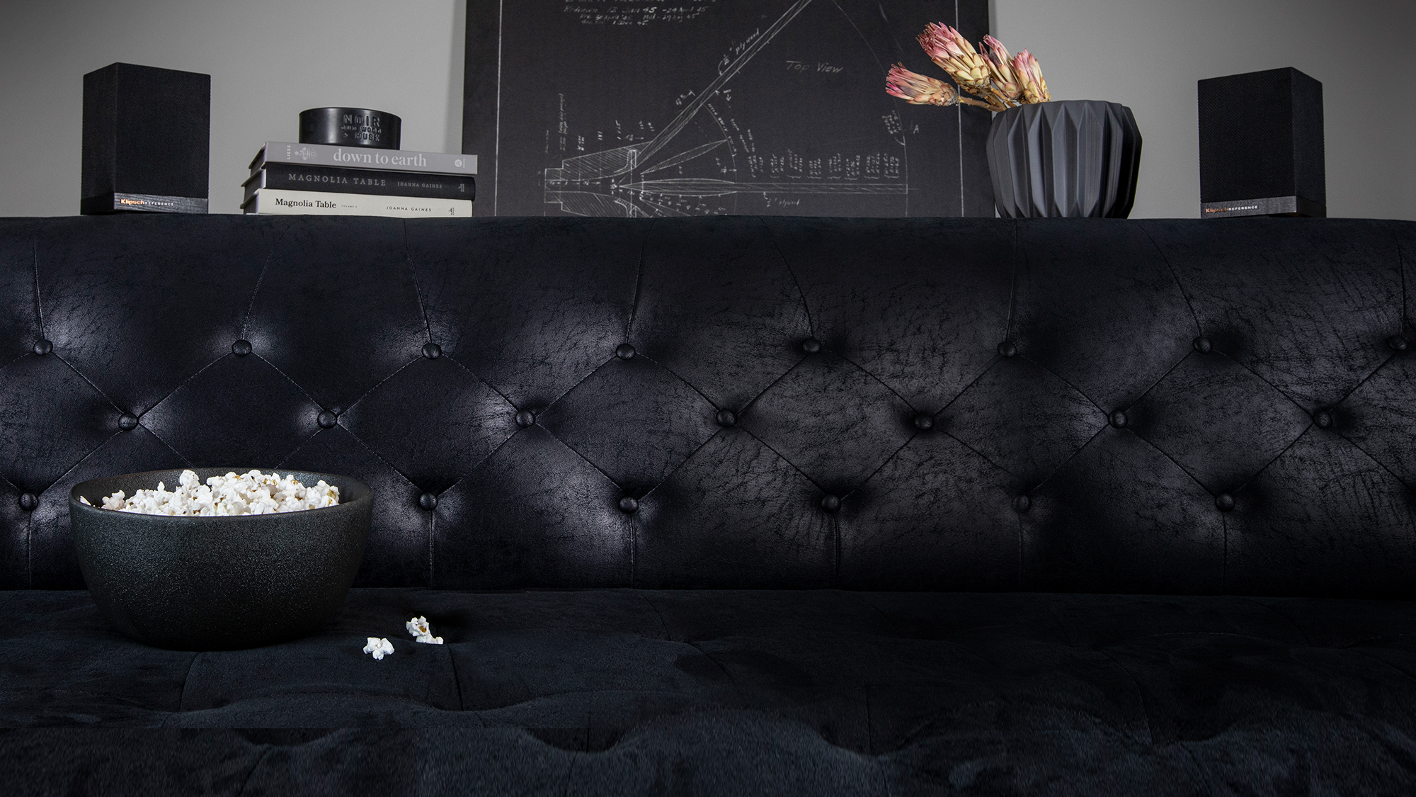 Klipsch Surround 3 wireless speakers behind a couch with popcorn on it desktop