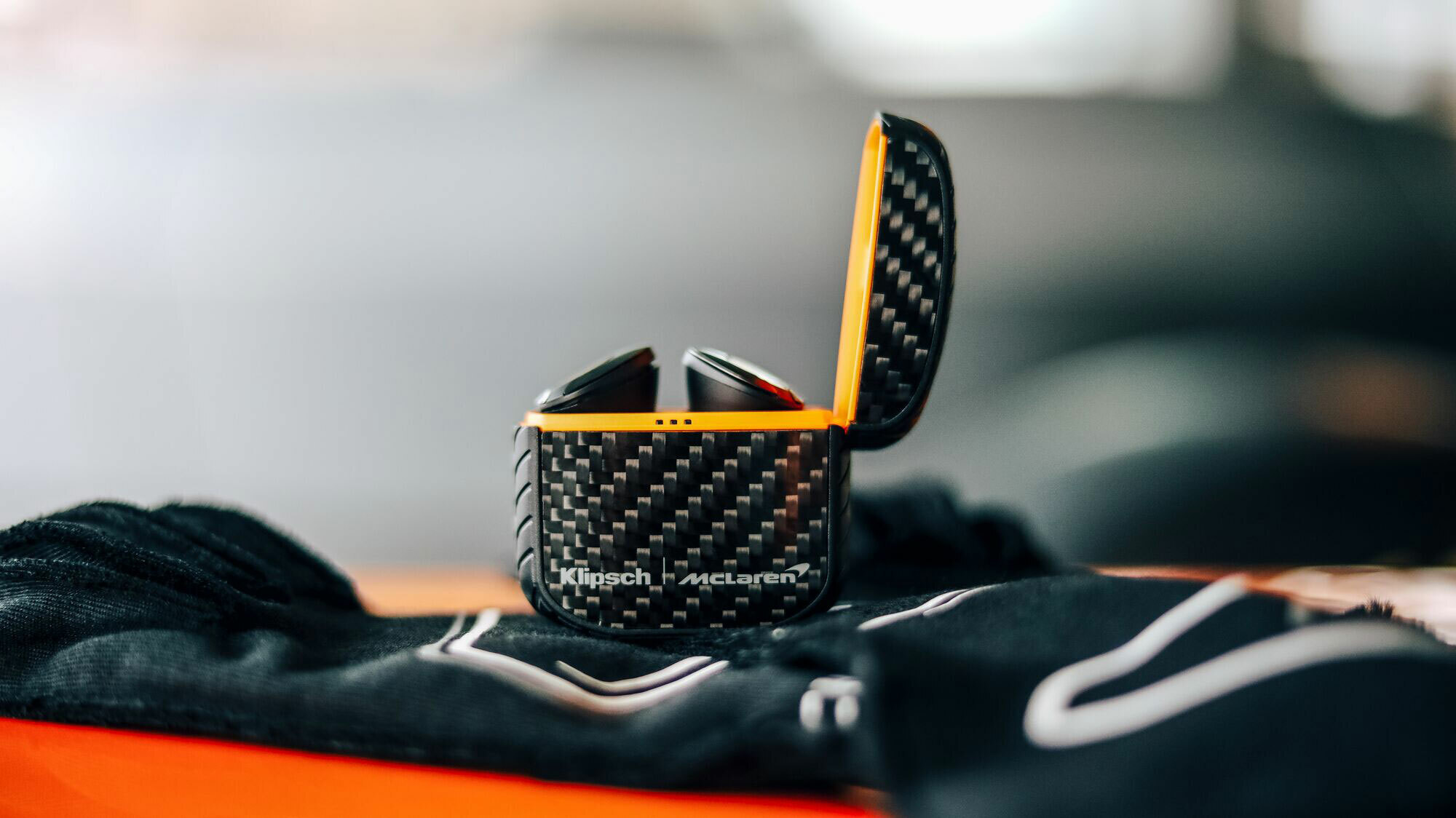 Klipsch T5 II ANC Mc Laren Edition earphones on driving gloves