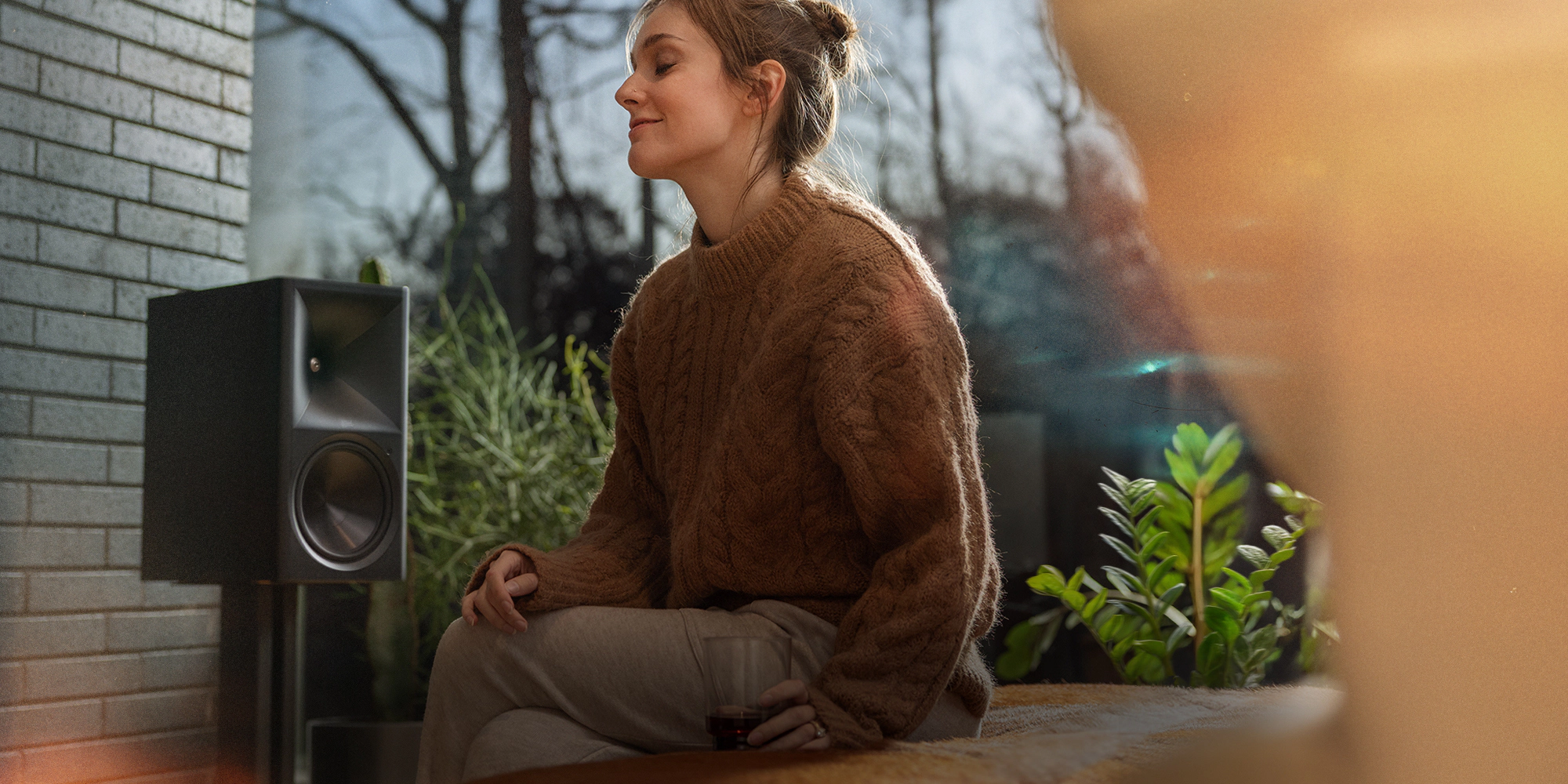 Klipsch The Nines II powered speaker beside woman enjoying the music 2000x1000