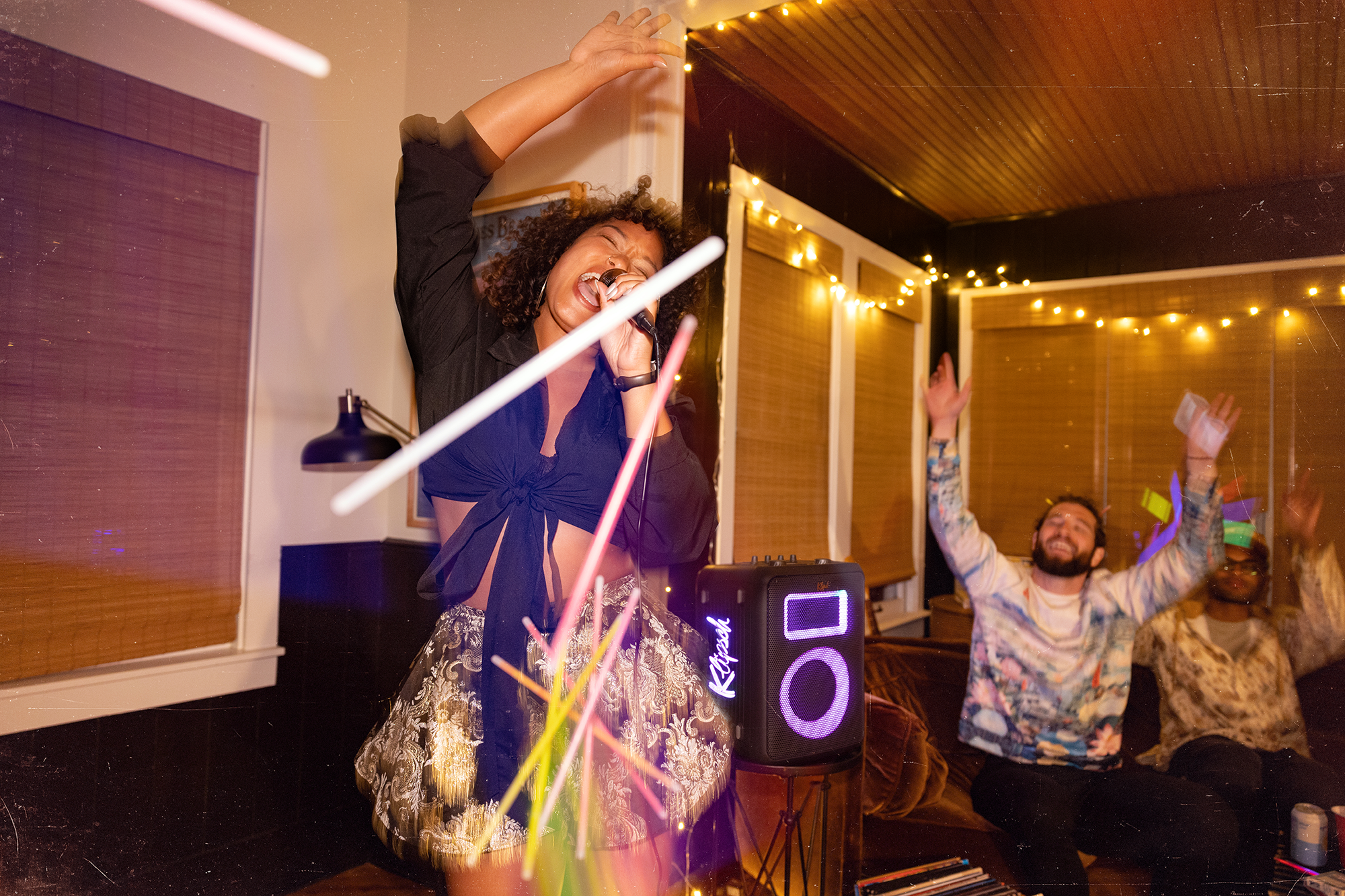 Klipsch Vegas Party Speaker at party behind woman belting out her jam in karaoke 2000x1333