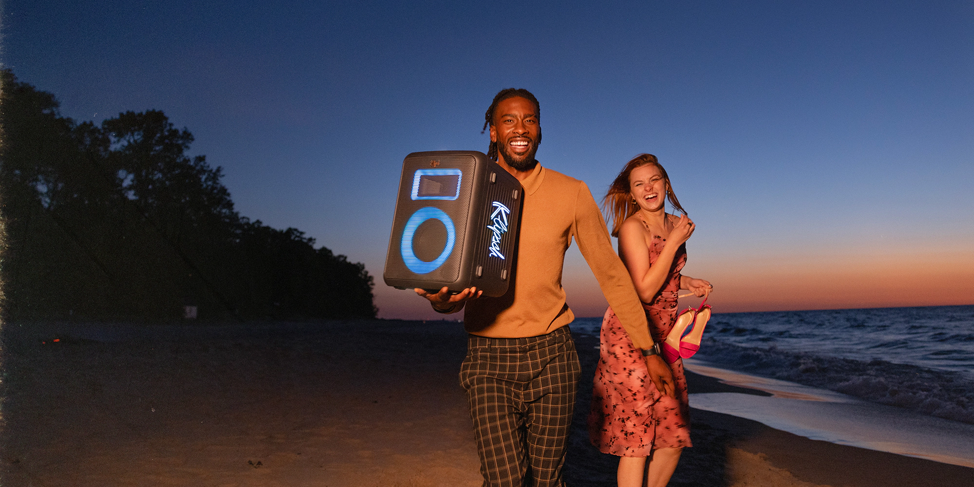 Klipsch Vegas Party Speaker in friends hands running on the beach laughing 2000x1000b