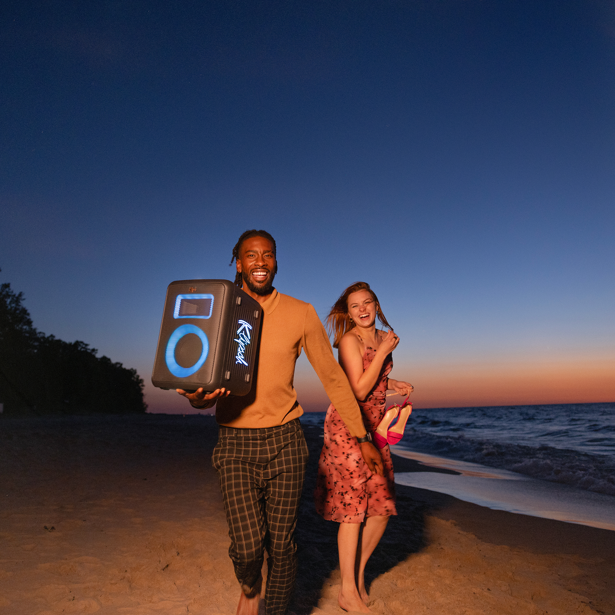 Klipsch Vegas Party Speaker in friends hands running on the beach laughing 2000x2000