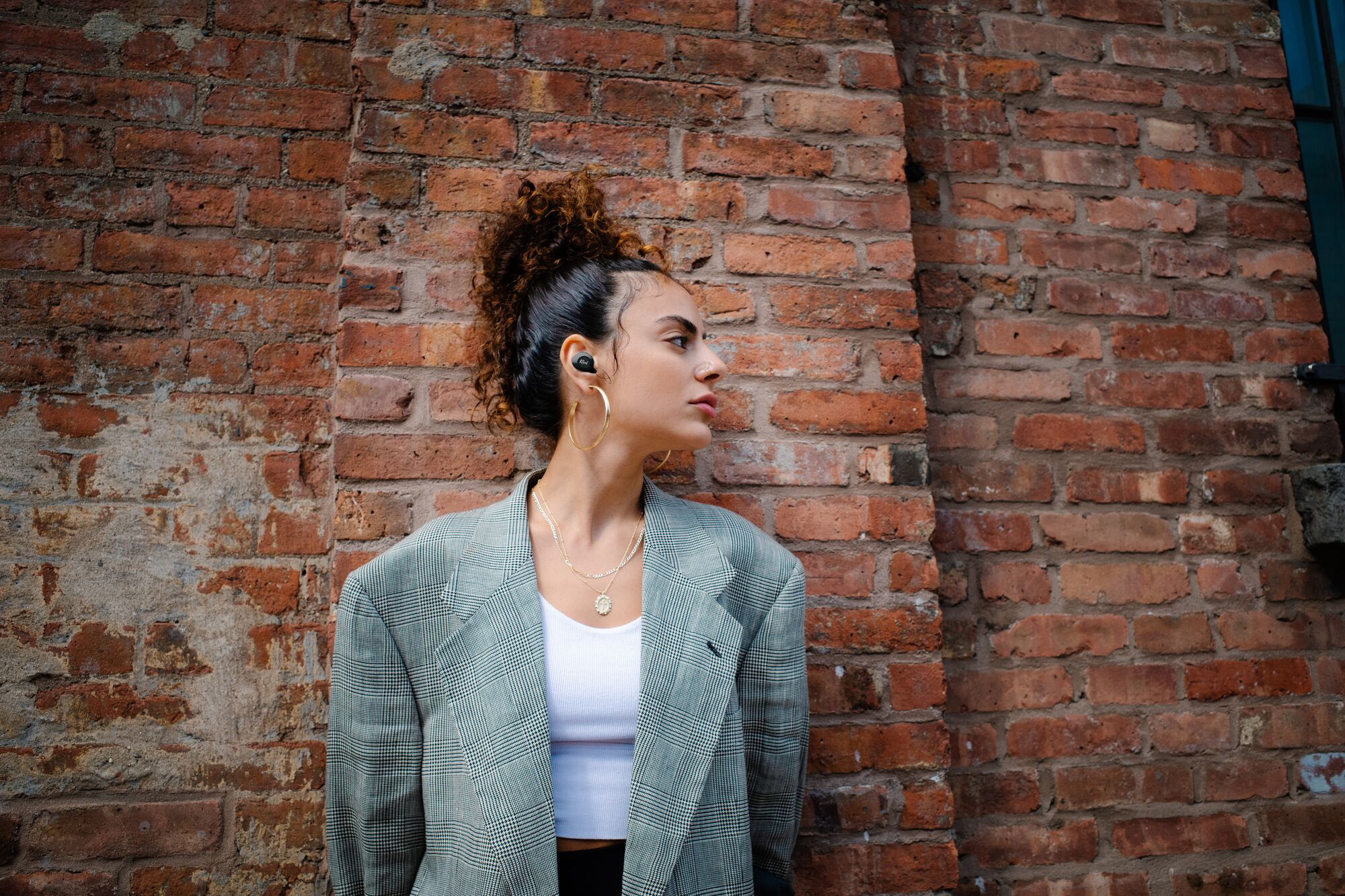 Klipsch active noise canceling earbuds woman against wall wearing earphones