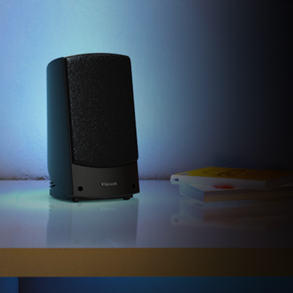 Promedia 2 0 Speaker on a table next to books mobile