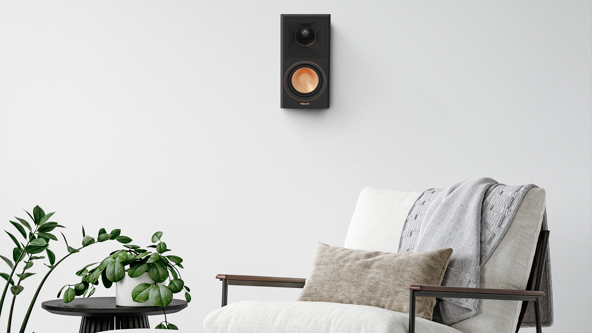 RP 500 SA II surround speaker hung on a greyish white wall near a chair