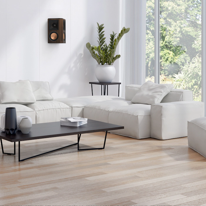 RP 502 S II surround speaker in walnut finish hung on a white wall near a living rooms corner mobile