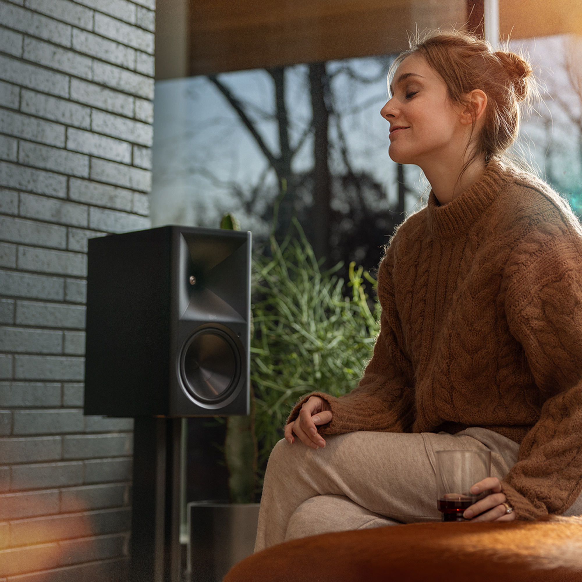 Woman enjoing music on The Klipsch Nines II perfectly tuned to the room with Dirac Live 2000x2000