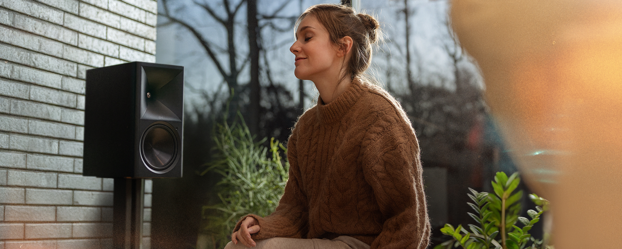 Woman enjoing music on The Klipsch Nines II perfectly tuned to the room with Dirac Live 2000x800