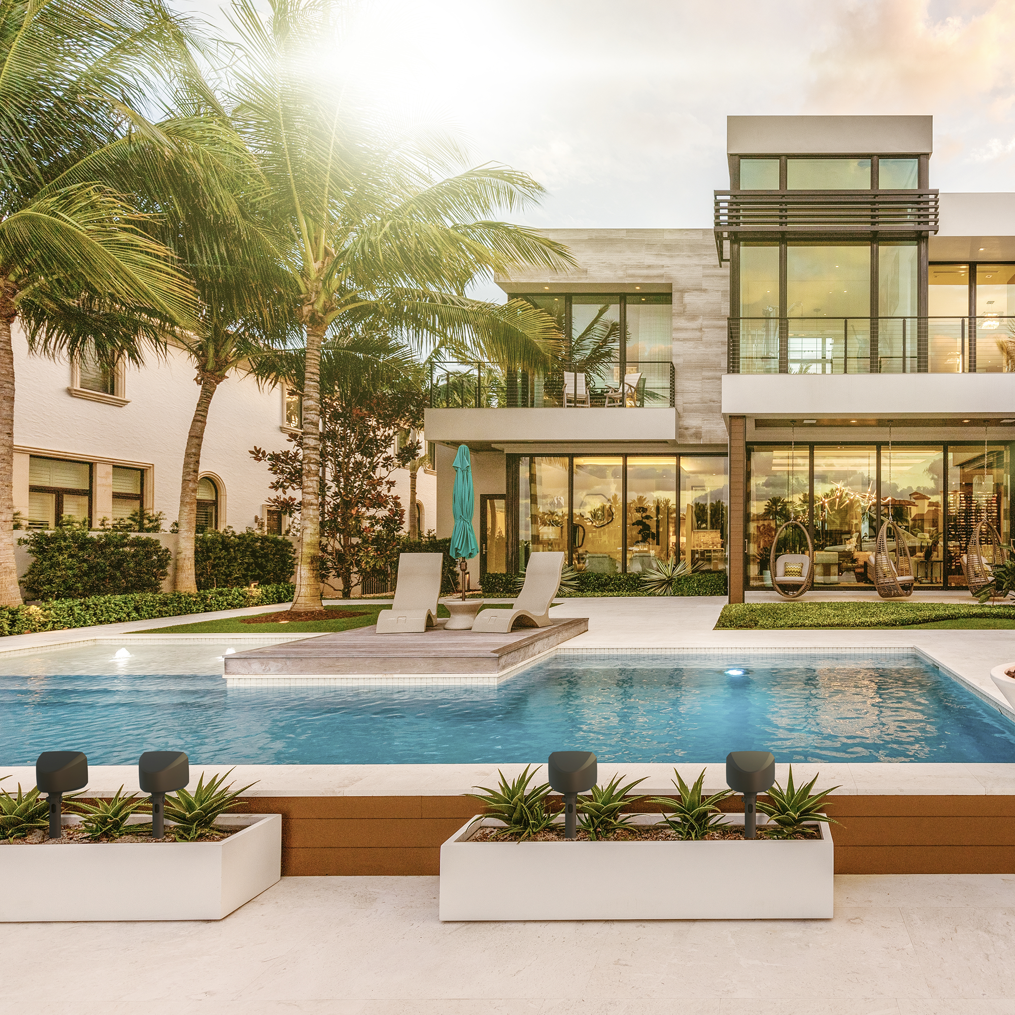 Klipsch Courtyard System in planters outside large mansion with palm trees 2000x2000