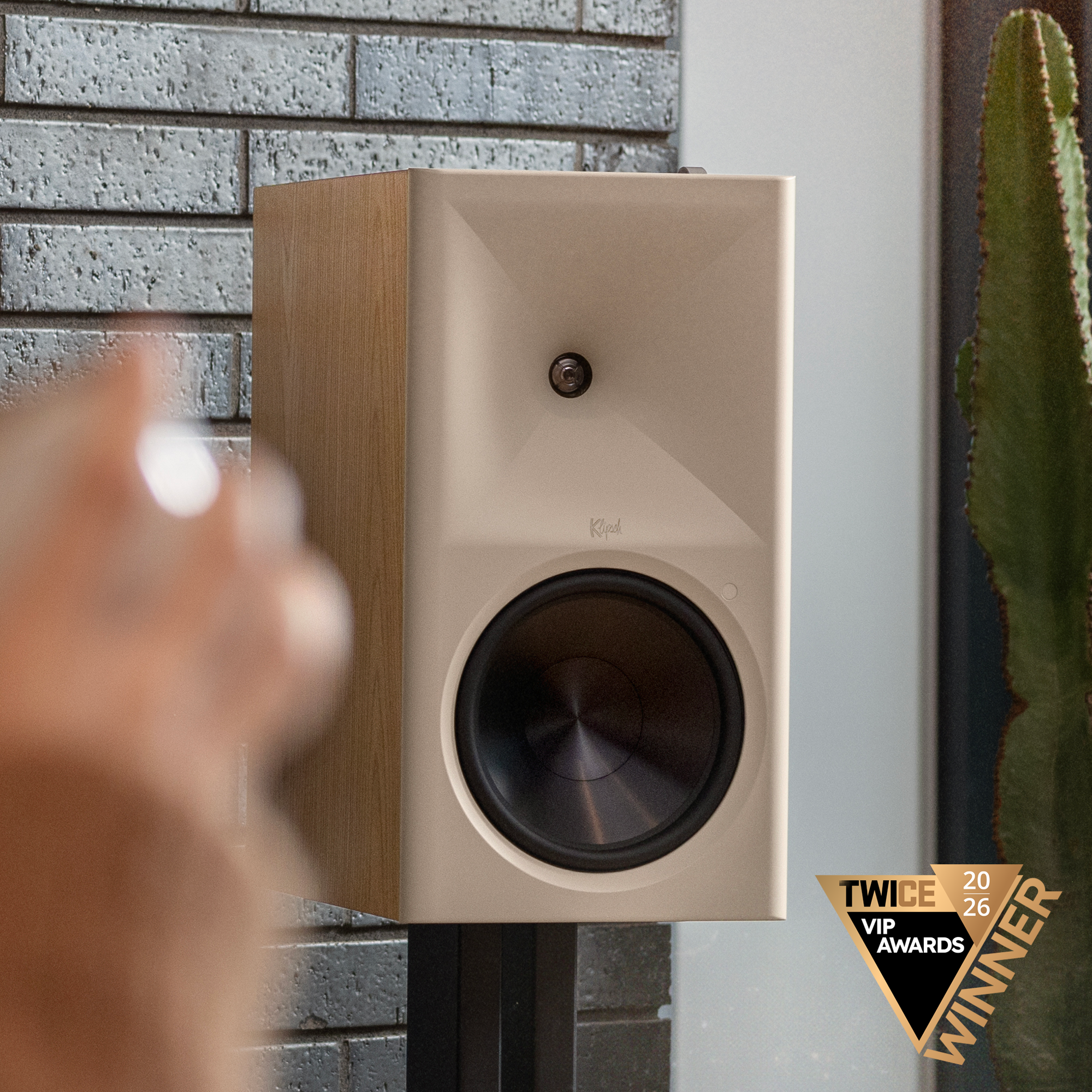 Klipsch The Nines RO on Klipsch bookshelf speaker stands beside cactus against brick feature wall TWICE Winner Badge 2000x2000