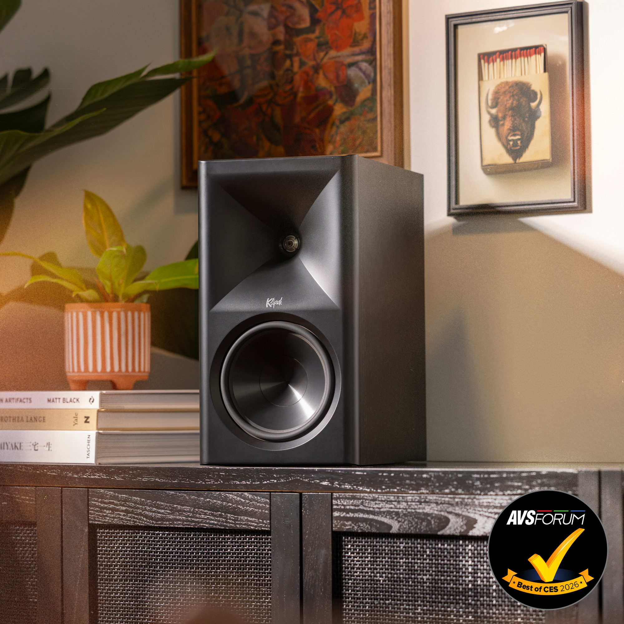 Klipsch The Sevens BK on modern media console beside plant and Americana art with warm lighting AVS Forum Best of CES Badge 2000x2000