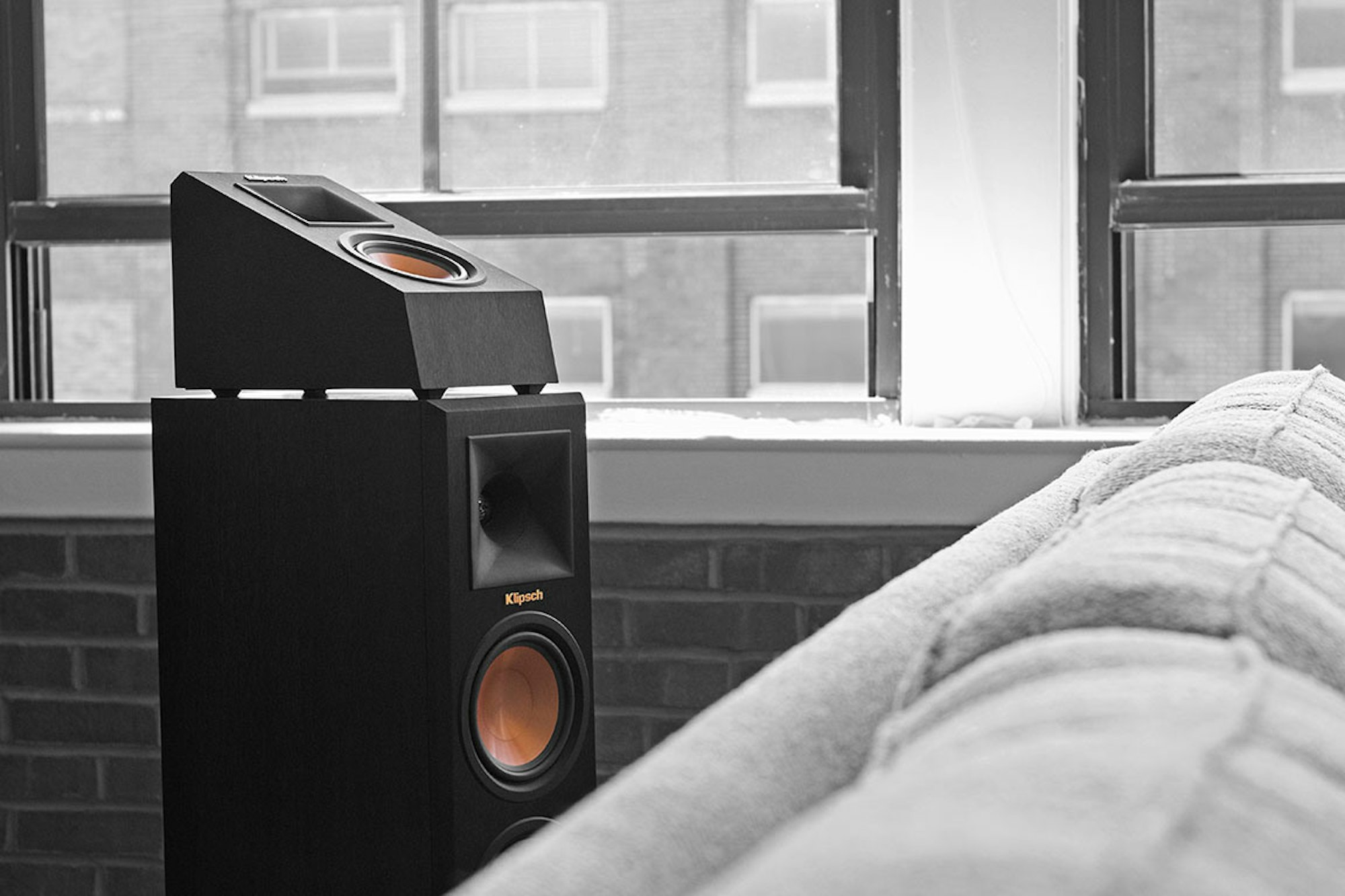Reference Premiere Dolby Atmos speaker next to black and white couch